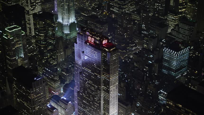 A breathtaking aerial shot of Manhattans Rockefeller Center at night with the camera flying away from the skyscrapers towards the city lights
