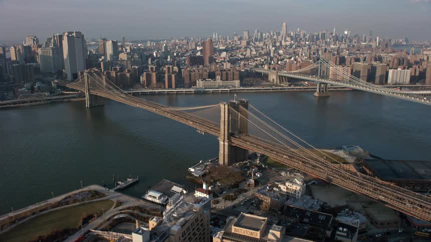 Aerial footage of Brooklyn Queens Expressway passing over the East River and Brooklyn Bridge on a clear winter day in New York City
