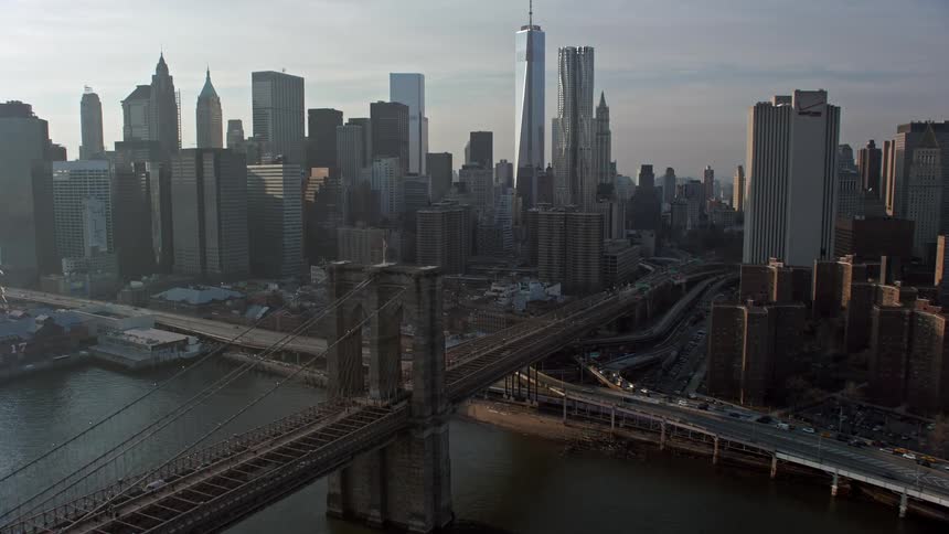 Approaching and flying over the iconic Brooklyn Bridge with a breathtaking view of the Lower Manhattan skyline on a sunny winter day in New York City