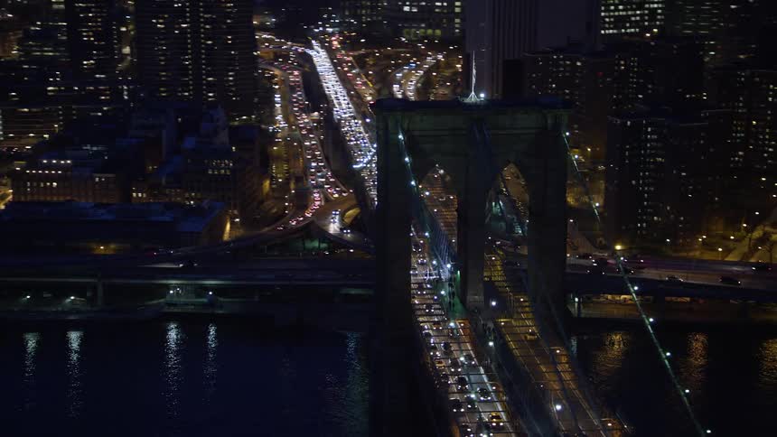 Aerial footage captures heavy traffic on the famous Brooklyn Bridge in Lower Manhattan during a clear winter night