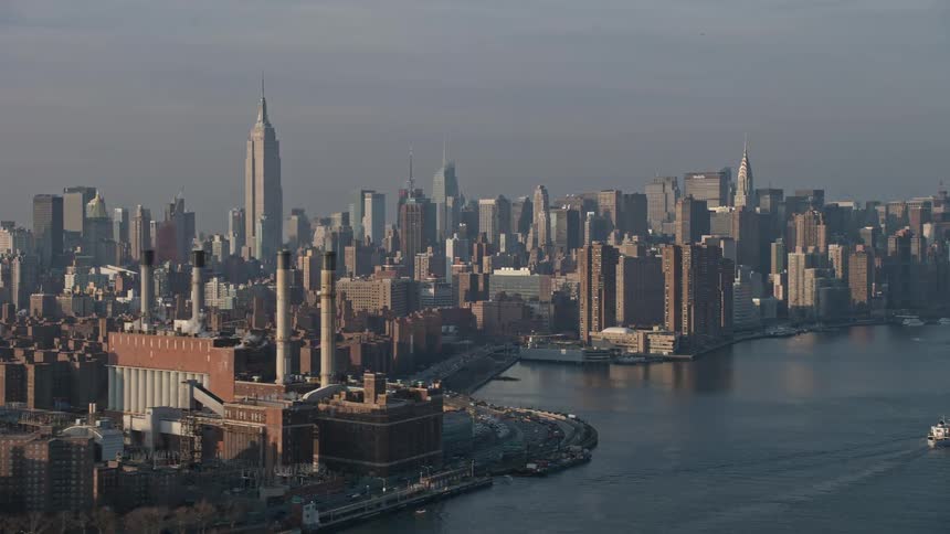 Aerial footage of Empire State Building and Midtown Manhattan skyline seen from a power plant by the East River on a sunny winter day in New York City