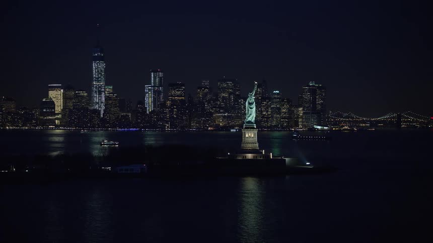 A beautiful Winter night shot of Lower Manhattan with the Statue of Liberty in the side view as the skyline of New York City approaches