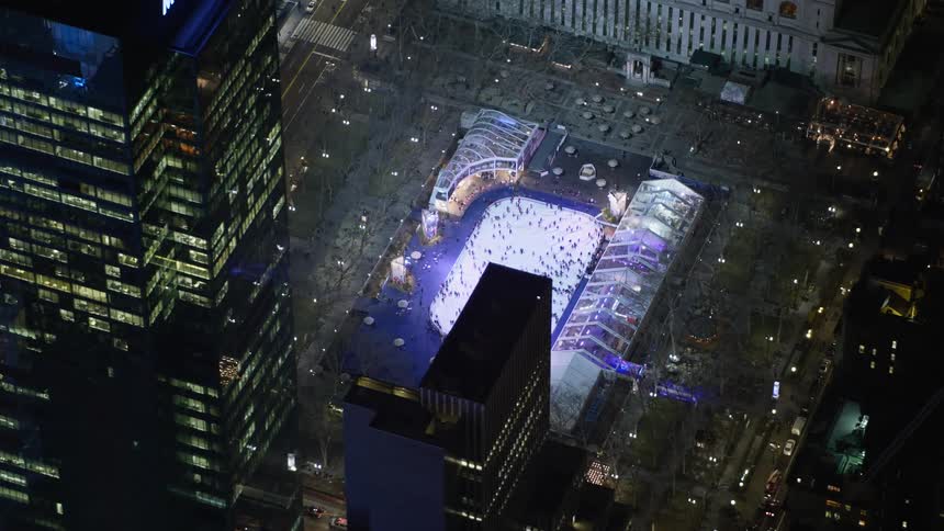 An overhead view of ice skaters circling around the rink at Bryant Park in Midtown Manhattan during a winter evening