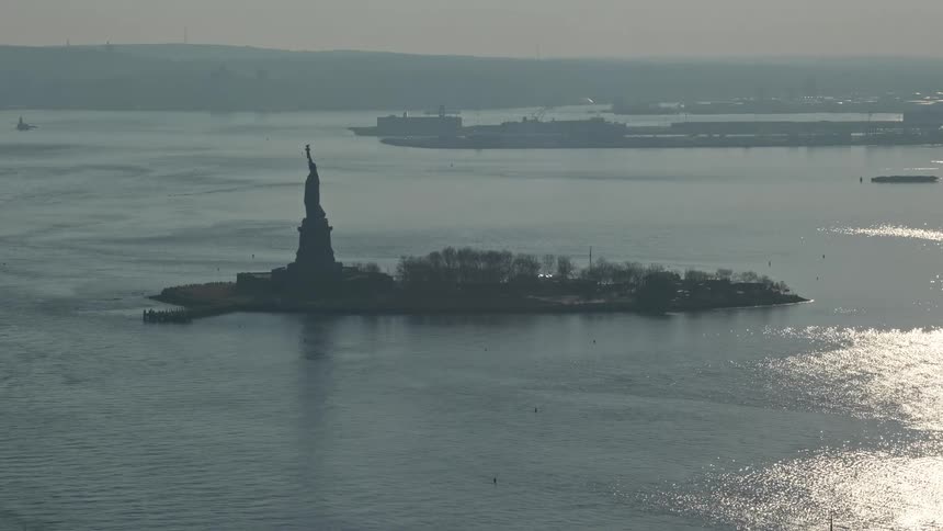 Approaching the iconic Statue of Liberty by aerial view on a hazy winter day in New York Harbor USA