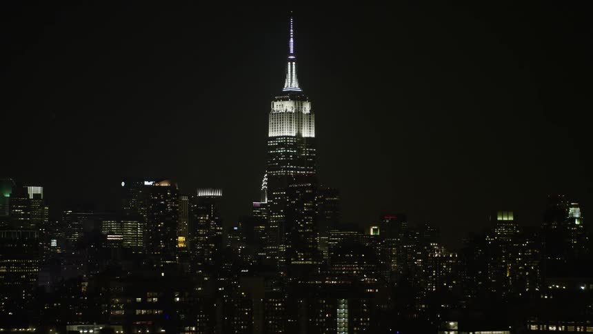 An awe-inspiring aerial view of the Empire State Building towering over New York City at night during winter without snow