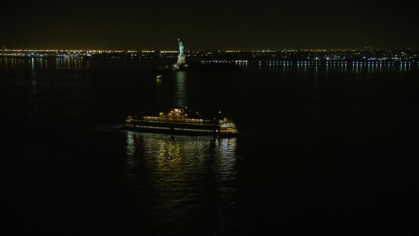 A stunning aerial nighttime shot of the Staten Island Ferry sailing through New York Harbor to reveal the Lower Manhattan skyline during winter