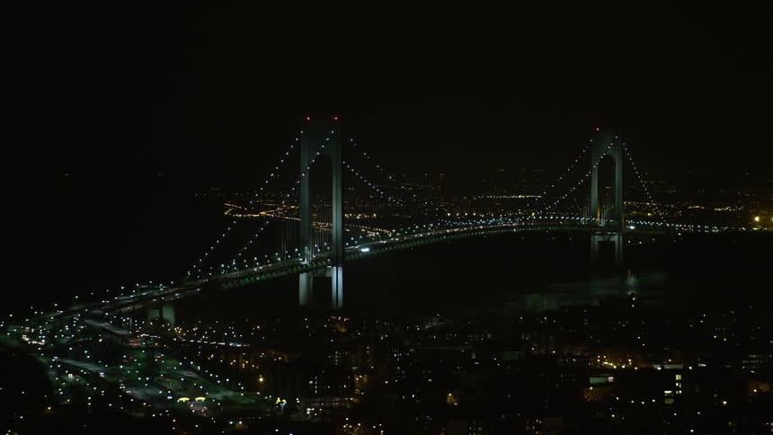 Aerial footage of traffic passing through the Verrazano-Narrows Bridge in New York City on a clear winter night