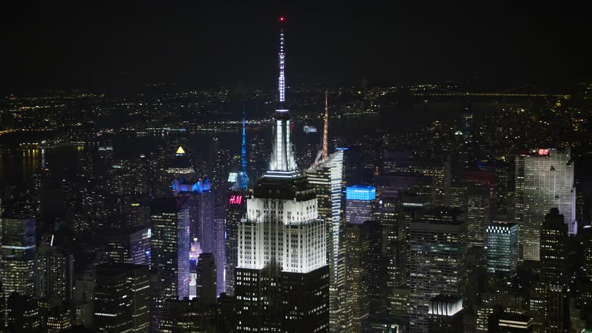 Aerial footage of the Empire State Building in Midtown Manhattan New York City at night during winter with a clear sky