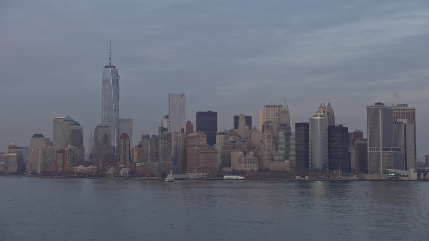 Approaching Lower Manhattans iconic skyline featuring One World Trade Center and Freedom Tower during sunset over New York Harbor in winter