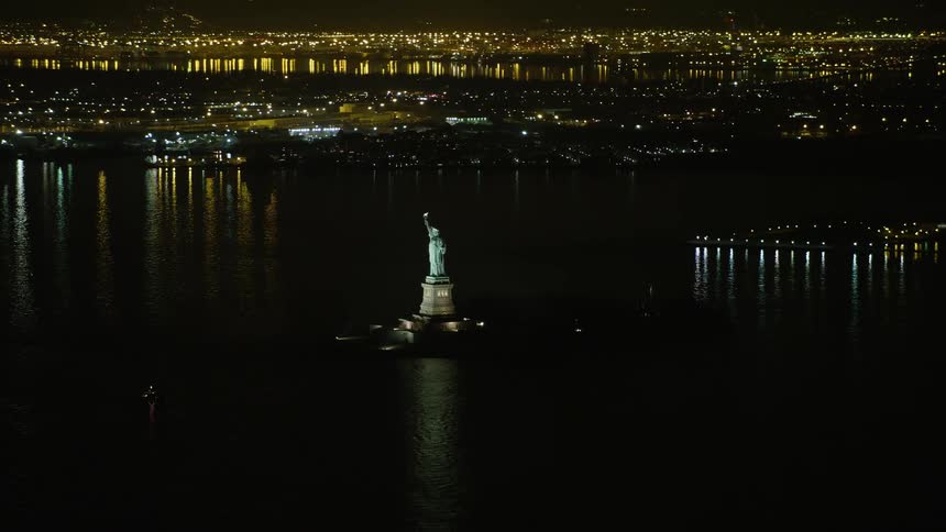 Aerial footage of the iconic Statue of Liberty monument on Liberty Island New York at night during the winter season