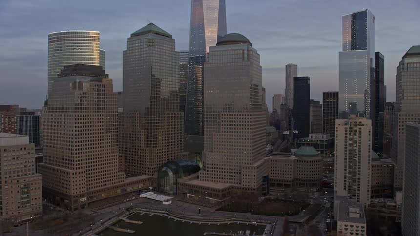 Aerial footage flyby of World Trade Center skyscrapers in New York City at dusk with a tilt up to the top of Freedom Tower during a winter sunset