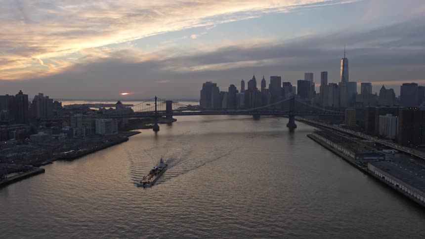 An aerial view of the Brooklyn and Manhattan bridges over the East River showcasing the iconic Lower Manhattan skyline during sunset on a winter evening shot from the Lower East Side public housing complex near the Williamsburg Bridge