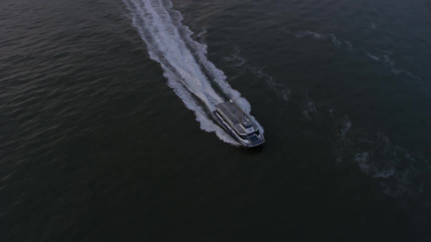 A NY Waterways ferry sails through New York Harbor during twilight in winter