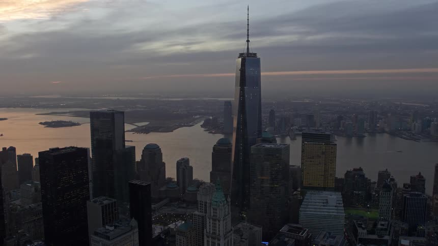 An aerial shot of the World Trade Center skyscrapers and One World Trade Center tower in Lower Manhattan during sunset on a cloudy winter evening