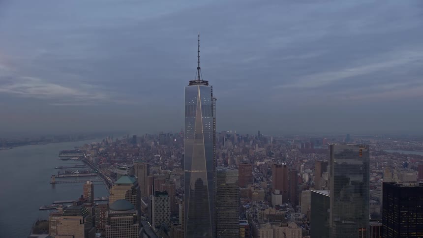An aerial orbit of Freedom Tower in Lower Manhattan with Hudson River and Midtown in the background during winter sunset