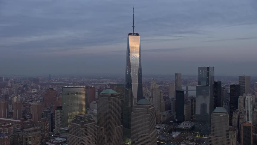 As the sun sets over the city an orbit shot captures the stunning view of Freedom Tower in Lower Manhattan with Hudson River and Midtown in the background showcasing the famous landmark of New York City