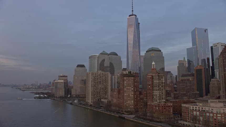 Approaching the iconic World Trade Center and Freedom Tower in Lower Manhattan during a cloudy winter sunset from a low altitude