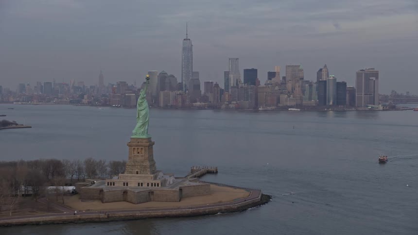 Aerial winter footage of the Statue of Liberty on Liberty Island as Lower Manhattans skyline serves as the stunning backdrop shot during twilight
