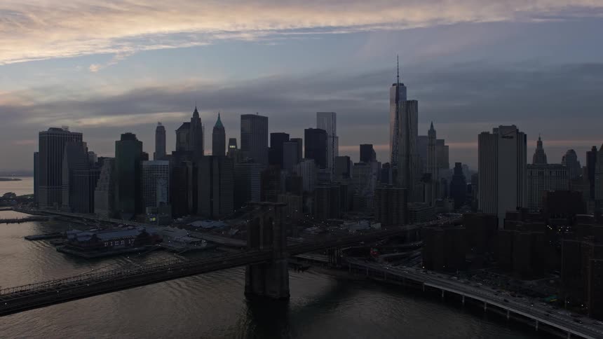 An aerial view at twilight showcases the iconic Brooklyn and Manhattan Bridges and the Lower Manhattan skyline in winter without snow in New York City