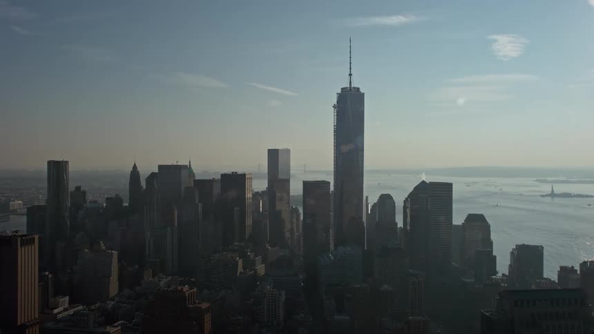 A breathtaking aerial view of One World Trade Center standing tall amidst the high-rise buildings of Lower Manhattan on a hazy winter day in New York City