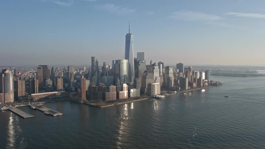 Flying over the Hudson River towards the Lower Manhattan skyline capturing iconic structures like One World Trade Center and skyscrapers in the winter setting