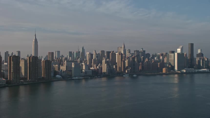 A breathtaking aerial view of the Empire State Building riverfront high-rises and Midtown skyline in New York City showcasing its historical landmarks and vibrant metropolis on a sunny winter day