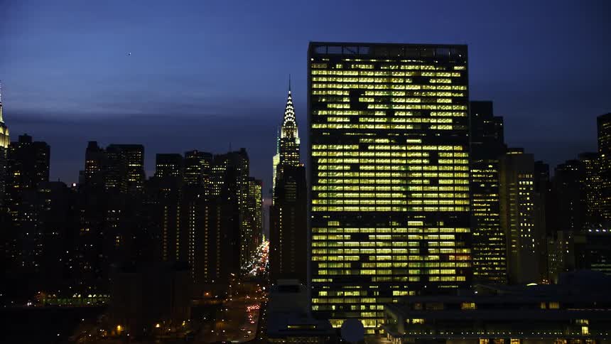 Aerial footage of iconic landmarks including the Chrysler Building and United Nations at night in winter over Midtown Manhattan in New York City