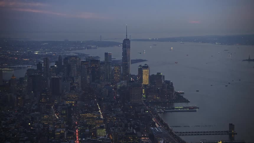 An aerial view of the lower Manhattan skyscrapers One World Trade Center and New York Harbor at twilight during winter without snow