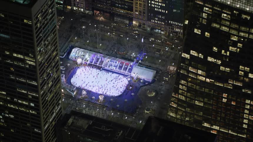 An aerial shot of an ice skating rink at Bryant Park in Midtown Manhattan at night during winter