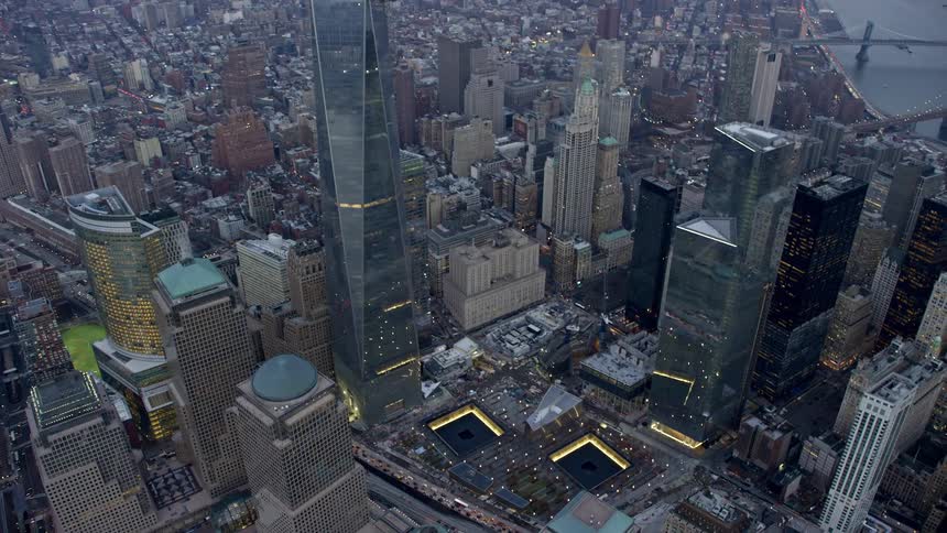 Aerial footage of World Trade Center Memorial and Freedom Tower in Lower Manhattan New York City during winter twilight showcasing the iconic landmarks of the city from a birds eye view
