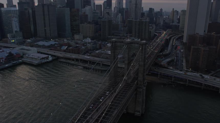 Aerial footage tracking the Brooklyn Bridge with heavy traffic in the winter twilight showcasing the iconic landmark and transportation hub of New York City