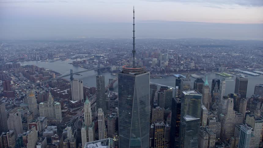 Aerial footage of the World Trade Center Memorial and Freedom Tower in Lower Manhattan New York City during twilight winter hours with a birds-eye view and a tilt-up and orbit around Freedom Tower