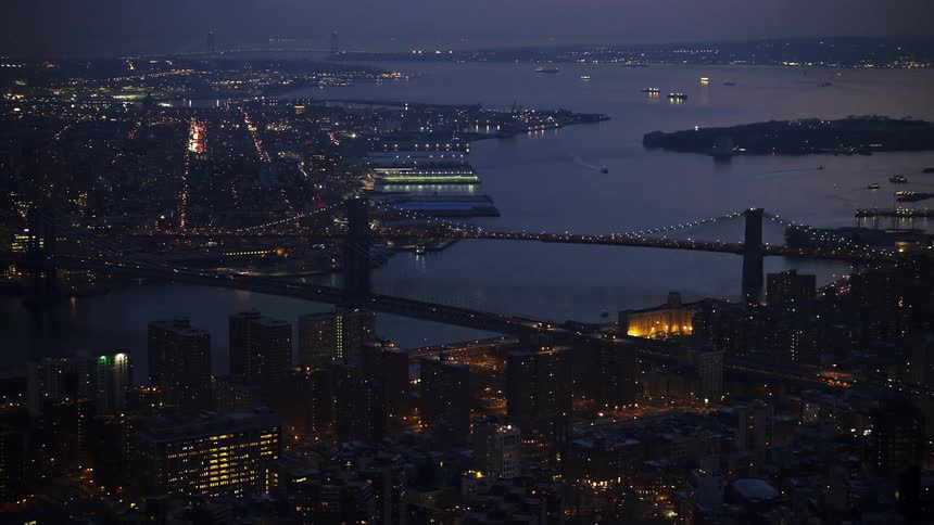 View of Manhattan and Brooklyn Bridges spanning East River at twilight with the Brooklyn skyline in the background during winter