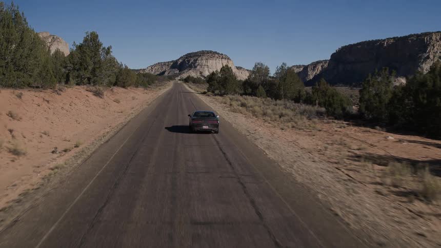 A car driving down a deserted road near a mountain