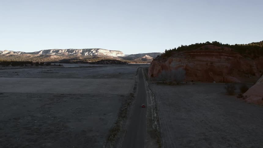 A car drives down a road near a desert