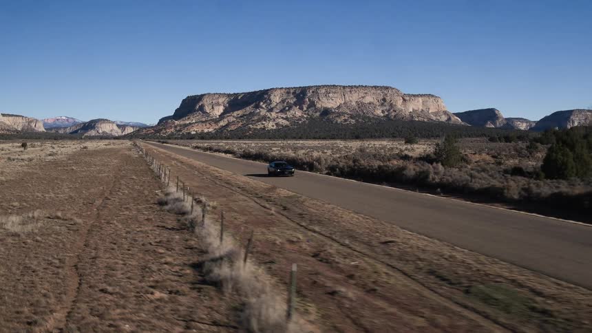 The car is moving down a road with a canyon behind