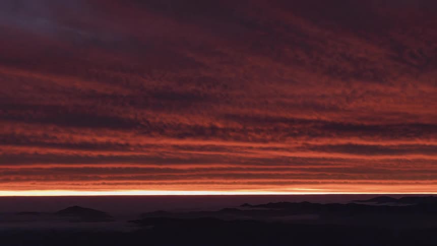Clouds of shifting color are seen above the horizon