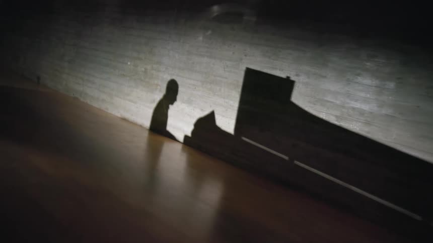 A silhouette of a person playing a piano is displayed