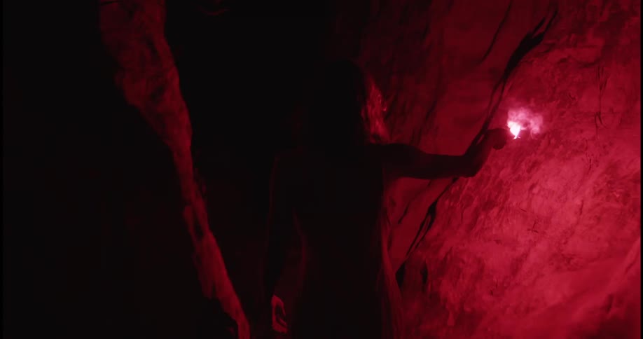 A woman is walking through a cave during the night time