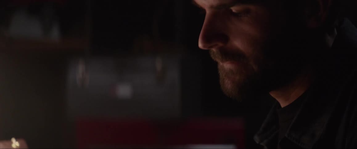 Light shines on the face of a man as he writes something on paper with a pencil
