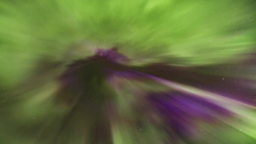 Green and purple lights of the aurora borealis move across the night sky