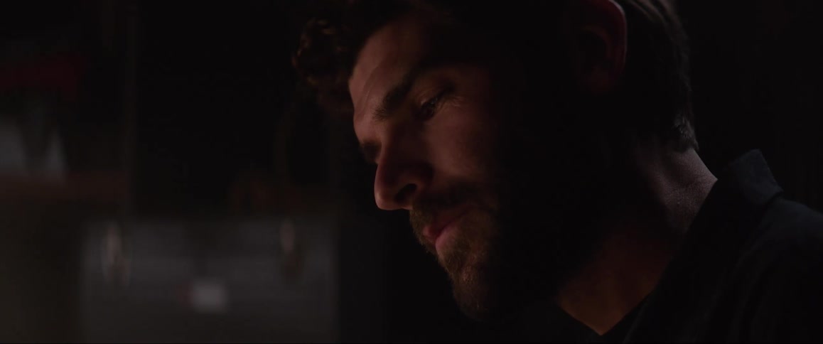 Light shines on the face of a man as he sits in the darkness
