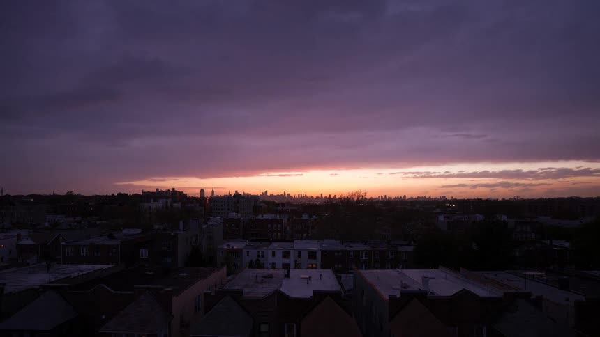 Sun sets over city as clouds more across the sky