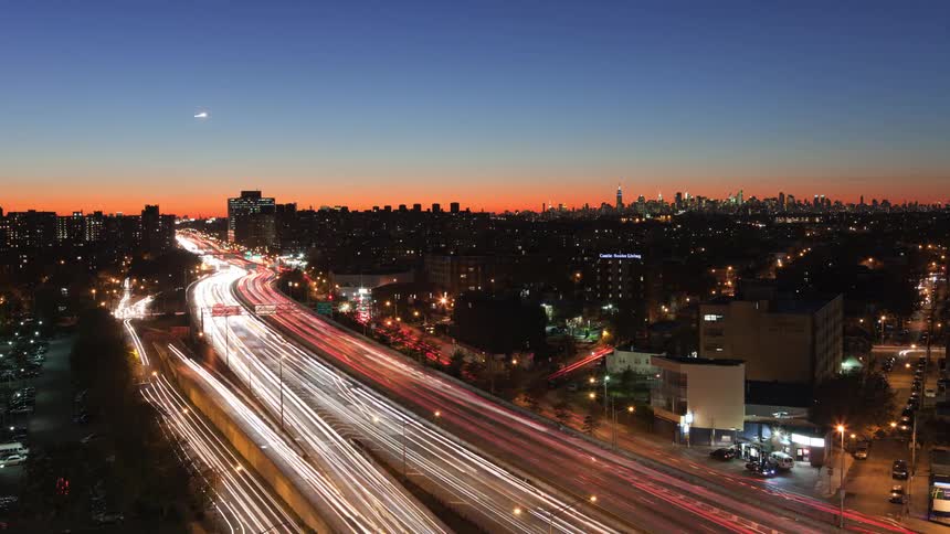 Aerial view of heavy traffic on highways and city skyline at dusk and night