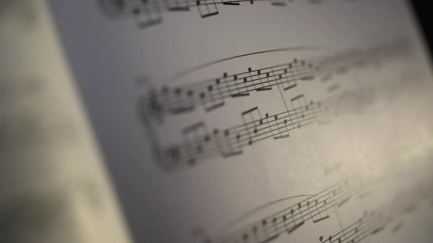 A camera sweeps over sheets of music