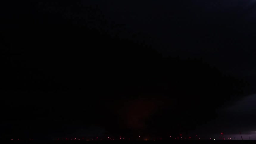 Lightning is flashing in the night sky and illuminating clouds
