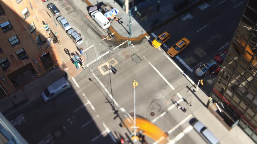 Aerial view of busy intersection with traffic and pedestrians walking down the street in the city