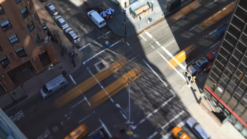 Pedestrians cross the road as traffic moves through an intersection in a city