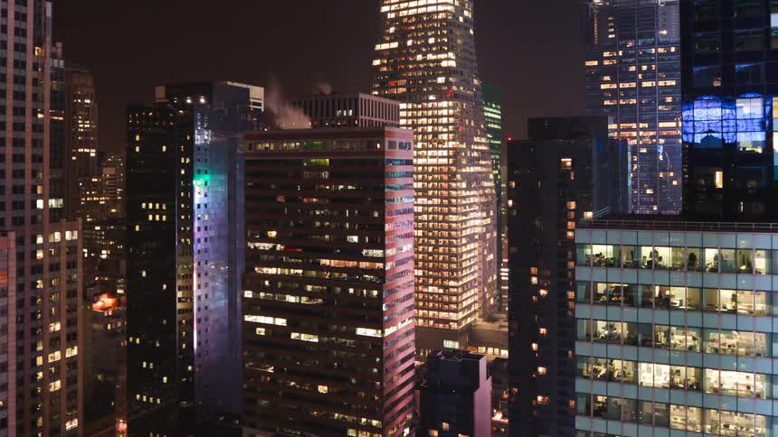 A city is lit up on most floors of several buildings during the night