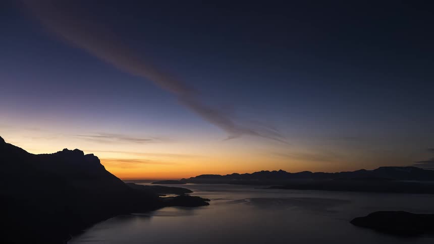 Clouds move over the lake and mountains and reflect on the water as the sky grows darker